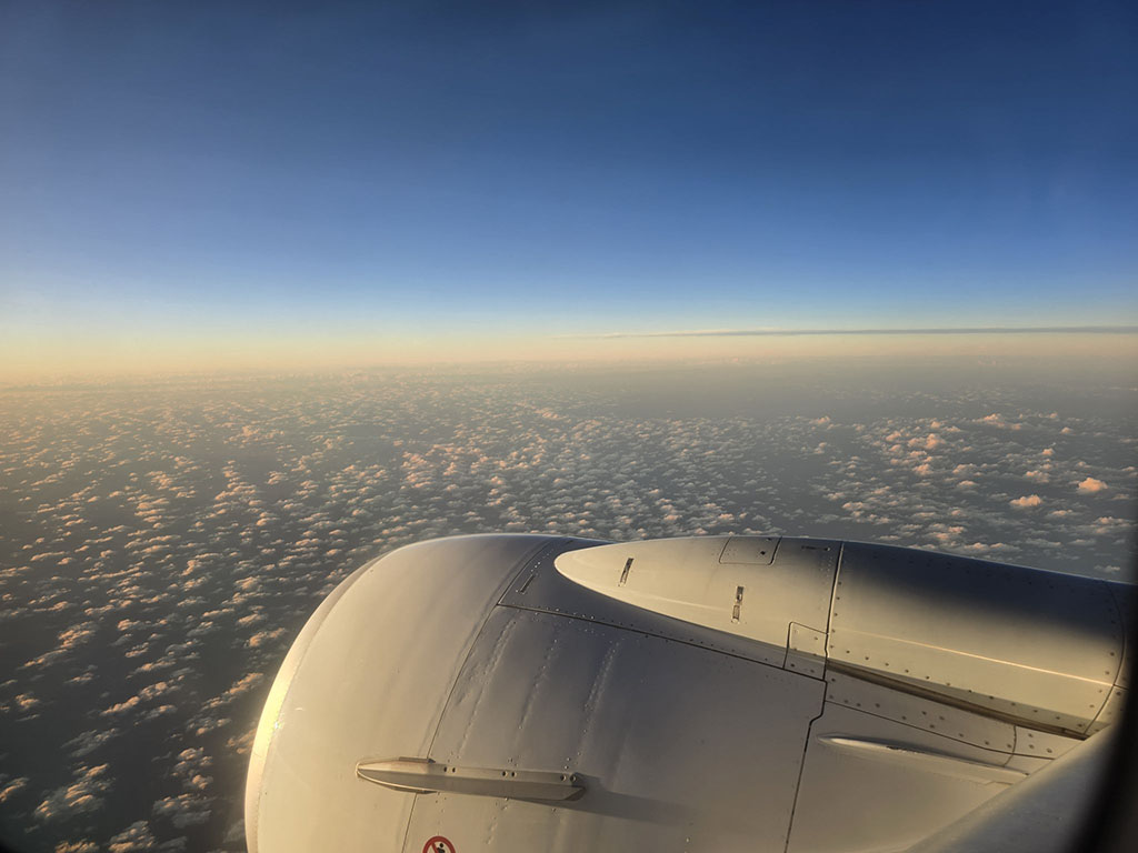 Airplane wing above clouds at sunset